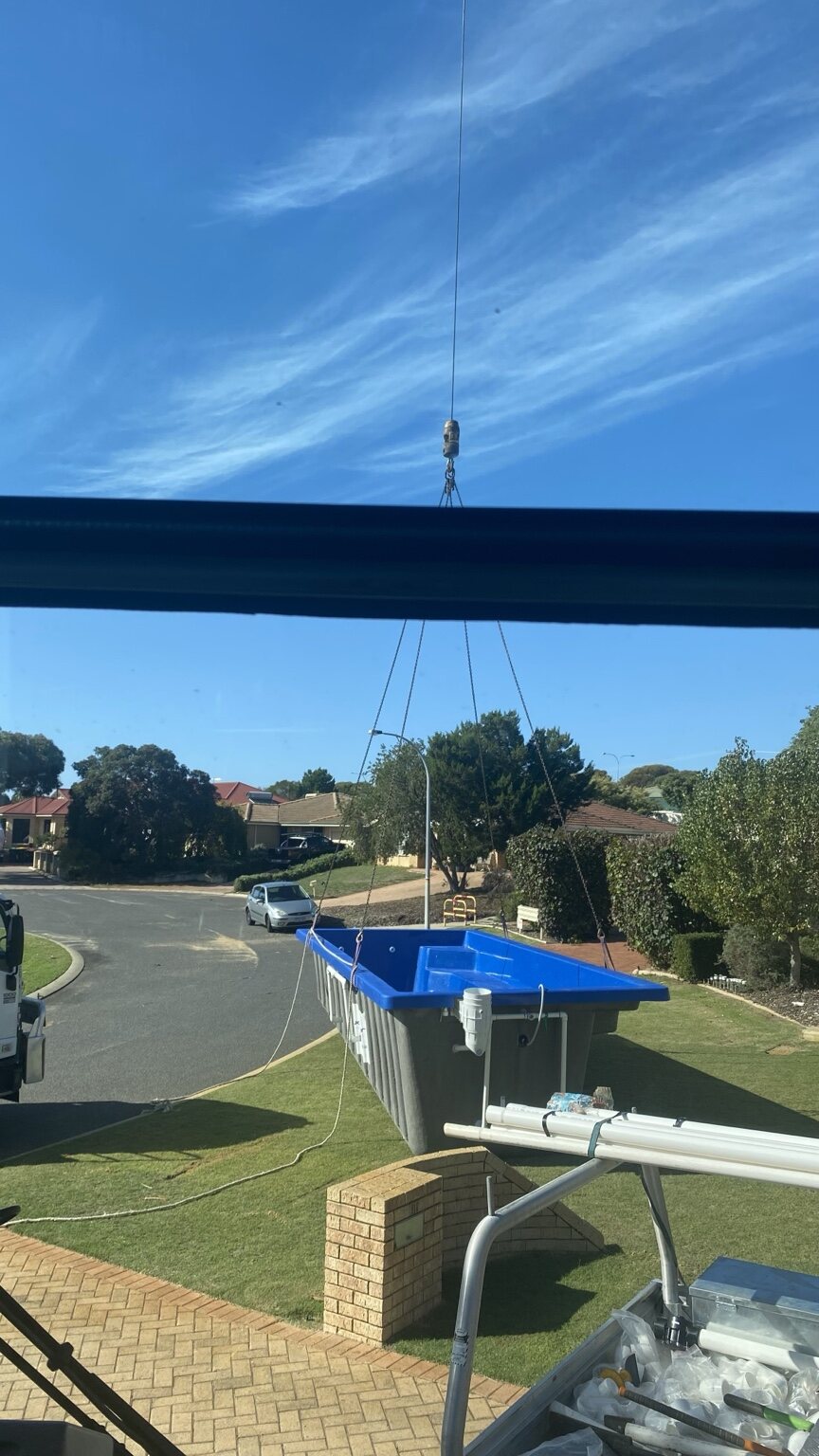 Swimming pool being lifted into a residential property by crane